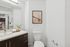 Bright modern bathroom featuring a sleek vanity, wall art, and view into a stylish kitchen.
