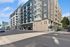 Contemporary apartment building with multiple balconies and modern design on a sunny street.