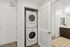 Efficient laundry area with a stacked washer and dryer next to a modern bathroom.