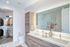 Elegant bathroom with dual sinks, luxury wooden cabinetry, and a spacious walk-in closet. Features a modern glass shower and stylish orchid decor.