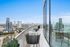 Luxurious high-rise balcony with panoramic city views, featuring a sleek glass facade and stylish outdoor seating.
