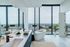 Sleek modern bathroom with a standalone bathtub and panoramic city views through floor-to-ceiling windows.