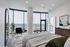 Luxurious bedroom with floor-to-ceiling windows offering stunning city views, modern decor, and sleek furnishings.