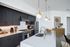 Sleek modern kitchen with elegant black cabinetry, stylish gold-accented appliances, and chic pendant lighting, perfect for gourmet cooking.