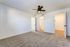 Bright and spacious bedroom with plush carpet, ceiling fan, and ample closet space in a modern apartment.