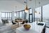 Luxurious open-concept apartment with modern dining area, sleek kitchen island, and panoramic city views from floor-to-ceiling windows.