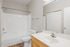 Bright, modern bathroom featuring a pristine white bathtub, sleek vanity with large mirror, and elegant wood accents.