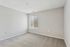 Bright and spacious empty room with soft carpeting and a large window providing ample natural light.