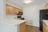 Modern kitchen with light wood cabinets, sleek countertops, and stainless steel appliances accented by warm wood flooring.