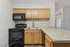 Charming kitchen with sleek black appliances, granite countertops, and modern light wood cabinetry.