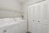 Modern laundry room with sleek white washer and dryer, convenient shelving, and ample storage space.