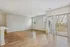 Bright and airy living space with sleek wooden flooring, large windows, and sliding glass doors leading to a tranquil outdoor view.