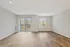 Spacious living area with elegant wood flooring, large windows, and abundant natural light, creating an inviting and modern ambiance.
