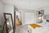 Cozy bedroom with modern decor, featuring a comfortable bed, stylish shelving, soft carpeting, and a large mirror reflecting natural light.