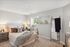 Bright and cozy bedroom with chic decor, showcasing a plush bed, modern side tables, and a large window for natural light.