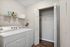 Modern laundry room with sleek appliances, ample shelving, and spacious closet, featuring stylish wood flooring.