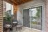 Inviting apartment patio with cozy seating, lush greenery, and sliding glass door overlooking landscaped area.