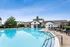 Inviting community pool area with a modern clubhouse, surrounded by lush landscaping and stylish lounge chairs for relaxation.