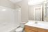 Bright and modern bathroom featuring a sleek vanity, large mirror, and pristine bathtub with elegant tile surround.