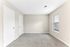 Bright, spacious room with fresh neutral walls, cozy carpeted floor, and ample sunlight through large windows.