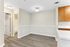 Modern apartment with elegant wood flooring, bright neutral walls, and a sleek adjoining kitchen featuring warm-toned cabinetry.