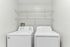 Modern laundry room featuring a sleek washer and dryer set, complemented by convenient overhead shelving for extra storage.
