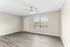 Bright and spacious room with modern gray flooring, ceiling fan, and large window offering natural light.
