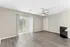 Bright living room with sleek laminate flooring, ceiling fan, and large windows with vertical blinds leading to a patio.