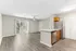 Bright open-concept living area with modern kitchen, sleek flooring, and natural light from sliding glass doors.