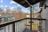 Charming balcony view from modern apartment overlooking serene wooded area and well-maintained parking lot.