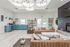 Bright and inviting living space with modern decor, featuring plush leather sofas, an elegant blue kitchen, and stylish shelving, perfect for relaxation and entertainment.