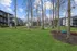 Charming apartment complex surrounded by lush green lawns and tall trees, featuring relaxing outdoor seating and picnic areas.