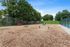 Inviting dog park surrounded by lush greenery with agility equipment, a secure fence, and vibrant red benches for comfort.