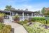 Inviting leasing center with charming porch, vibrant landscaping, and modern design under a clear blue sky.