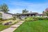 Charming single-story home with a welcoming front porch surrounded by vibrant landscaping and lush greenery.