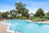 Inviting apartment complex pool surrounded by lush greenery, comfortable lounge chairs, and outdoor seating, perfect for relaxation.