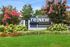 Inviting entrance to ReNew Harford Apartments surrounded by vibrant floral landscaping and lush greenery.
