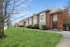 Charming brick apartment complex with manicured lawns and inviting pathways, perfect for modern living.
