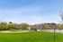 Vibrant view of a sunny park featuring a well-maintained baseball field, lush green trees, and clear blue skies.