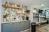 Chic apartment corner featuring a modern coffee station with tropical wallpaper, sleek storage solutions, and stylish open shelving.
