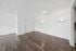 Bright and modern living area with sleek hardwood flooring, white walls, and ambient lighting.