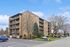 Inviting mid-rise apartment building with spacious balconies, surrounded by well-maintained greenery and ample parking.