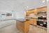 Bright and inviting open-concept living room with a modern kitchen, featuring wooden cabinets, stainless steel appliances, and a large window offering natural light.