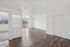 Bright, open-plan apartment with wooden flooring, elegant built-in shelving, large windows, and a balcony view.
