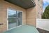 Inviting apartment balcony with sliding glass doors, featuring modern brickwork and a view of lush greenery.