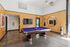 Chic recreational room featuring a sleek blue felt billiards table, modern wood panel walls, and a flat-screen TV, perfect for entertainment and relaxation.