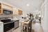Modern open-concept kitchen and living area with sleek appliances, cozy dining, stylish decor, and natural light from large windows.