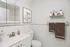 Chic white bathroom featuring a modern vanity, elegant floral artwork, and stylish wall-mounted toiletries.