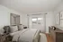 Bright and inviting bedroom with elegant decor, featuring large window views and sleek wooden furniture for a modern touch.