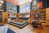Vibrant and modern lounge area featuring a cozy seating nook, stylish wooden bookshelves, and artistic wall decor under a high ceiling with large windows.